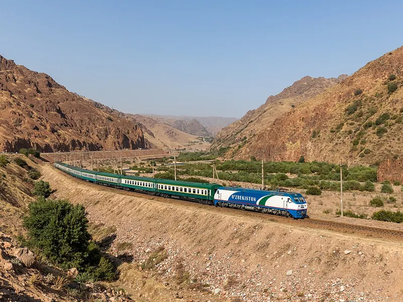 Conventional Uzbekistan Railways passenger train in a mountain valley